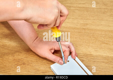 The furniture assembler tightens the furniture connector with furniture made of chipboard, flat pack furniture assembly, snap-together joints. Stock Photo