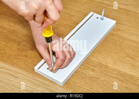 The product assemble tightens the connector bolts with furniture made of chipboard, flat pack furniture assembly service, snap-together joints. Stock Photo