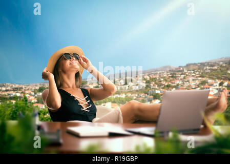 Woman in a swimsuit at the office table thinking about a travelling, landscape on background. Dreams about a vacation idea, daydreaming Stock Photo