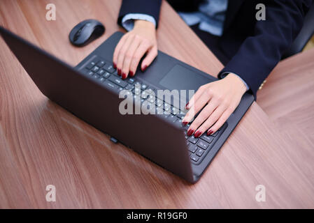 The girl works at a laptop in the office. Hands with laptop close up. Stock Photo