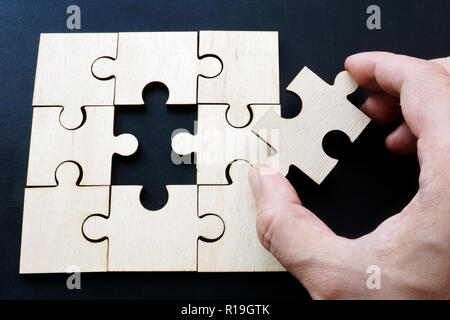 Hand is holding piece of jigsaw puzzle. Problem solving in business. Stock Photo