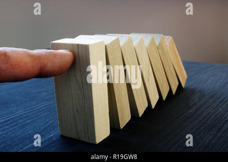 Business risk management concept. Hand holding blocks from falling. Domino effect. Stock Photo