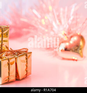 Happy Christmas, New Year, gifts in gold boxes and a golden heart on a background of pink and yellow bokeh Stock Photo