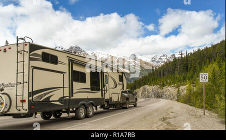 COLUMBIA ICEFIELD, ALBERTA, CANADA - JUNE 2018: Truck towing a big camping trailer on a road through the Columbia Icefield area in Alberta, Canada. Stock Photo