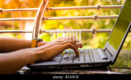 Young men Typing on Laptop Keyboard with green blur background, Stock Photo