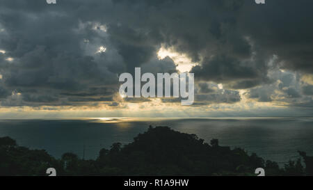 Sunrays comming through dark clouds over the sea Stock Photo