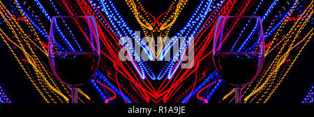 Glasses of wine on a background of abstract colored lights in motion. Multicolored lines of light on a black background. Stock Photo