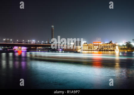 Cairo city center at night, long exposure with light trails of moving boats on the Nile river.