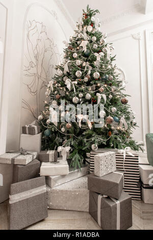 Presents and Gift boxes under Christmas Tree. Boxes with ribbon bow. New year decorated house interior. Winter Holiday concept. Stock Photo