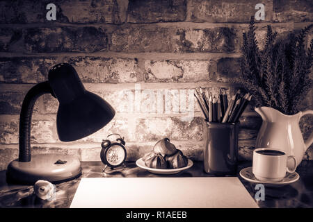 Colored pencils in a mug, vase of lavender flowers, clock, floor lamp, night light, plate of cakes, cup of coffee, white paper on a table against a br Stock Photo