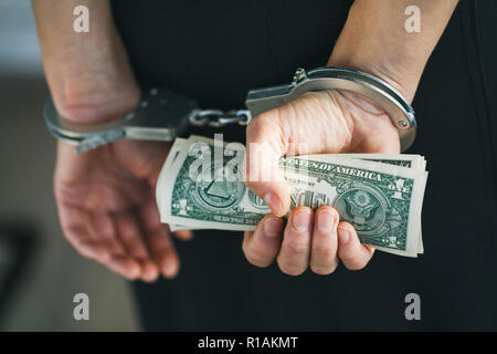 Hands in handcuffs with dollars, close-up Stock Photo