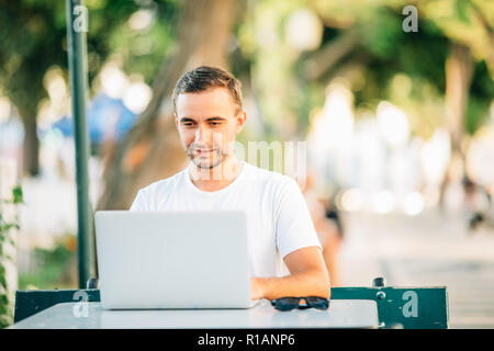 Happy freelancer hipster man communicating with his partners using laptop computer. Bearded man in jeans shirt working in the part. Stock Photo