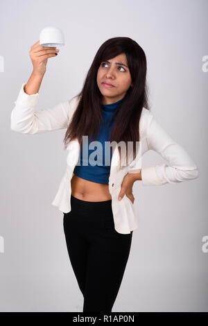 Studio shot of young Persian businesswoman standing while holdin Stock Photo