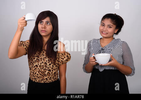 Studio shot of young Persian woman holding empty coffee cup upsi Stock Photo