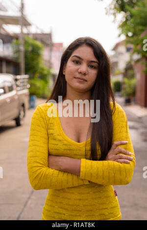 Close up of young Indian woman with arms crossed in the streets  Stock Photo