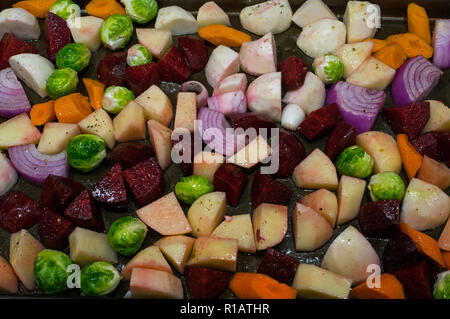 Autumn vegetables sliced and oiled prior to roasting. The medley includes potatoes, onion, beets, turnips, carrots, and brussel sprouts. Stock Photo