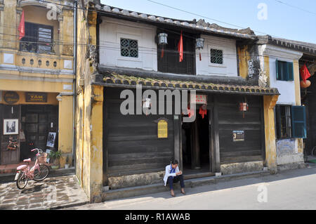 Hoi An, Vietnam - Apr. 13, 2011: Woman waits outside the old historic Tan Ky House, house that was certified as part of Hoi An's national heritage. Stock Photo