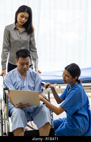 Physical therapist explain treatment method to senior patient and relative using notebook Stock Photo