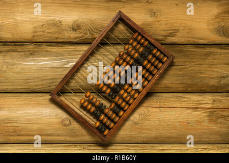 Old hand abacus hanging on a nail on the wall of wooden logs. Stock Photo