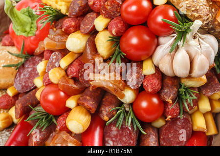Set consisting of different varieties of sausage, meat, smoked cheese, tomatoes, pepper and bread as background Stock Photo