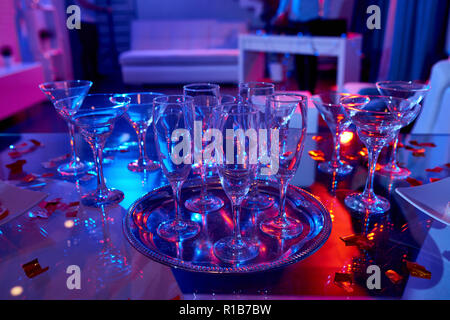Set of various alcohol glasses composed on shiny table in confetti with neon lights Stock Photo