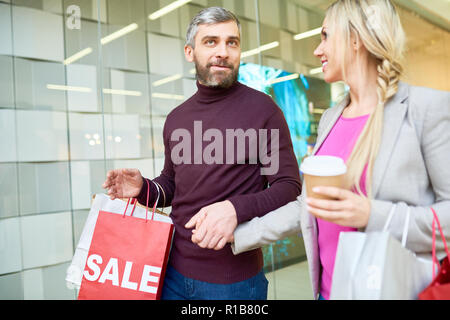 Portrait of adult couple shopping in mall and holding bags during SALE season Stock Photo