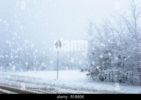 Speed limit traffic sign covered with ice on snowy winter background with falling snow Stock Photo