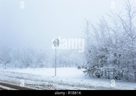 Speed limit traffic sign covered with ice and snow on snowy winter background Stock Photo