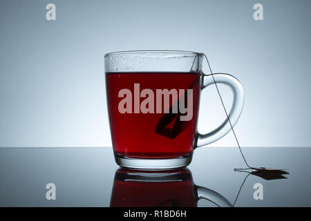 tea bag in a transparent mug with reflection on a grey background Stock Photo
