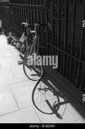 Broken bicycle chained to a railing on a street in London Stock Photo