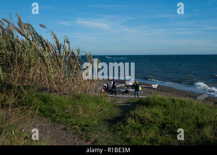 Police officers seen inspecting the dinghy after arriving on the beach with a group of migrants. A dinghy with migrants and two dead arrived at the Chilches beach near the coast of Velez Málaga, in Malaga. According to the media and witnesses, some of the migrants from Morocco escaped at the beach while the two corpses were found inside the small boat. Stock Photo