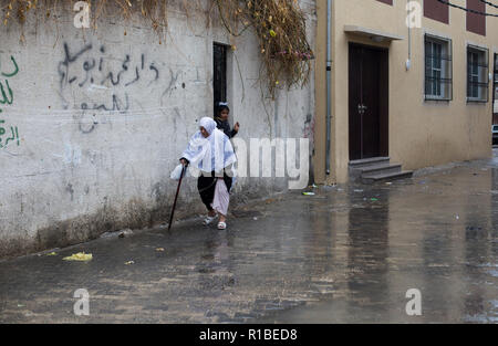 A Palestinian elderly woman seen walking on the street during a heavy rainfall in Gaza City. Stock Photo