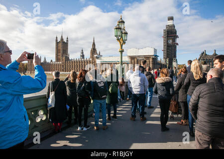 London, UK. 11th Nov, 2018. Members of the public on Westminster Bridge listen silently to the chimes of Big Ben to mark the eleventh hour of the eleventh day of the eleventh month in commemoration on Remembrance Sunday of the centenary of the signing of the Armistice which marked the end of the First World War. Credit: Mark Kerrison/Alamy Live News Stock Photo