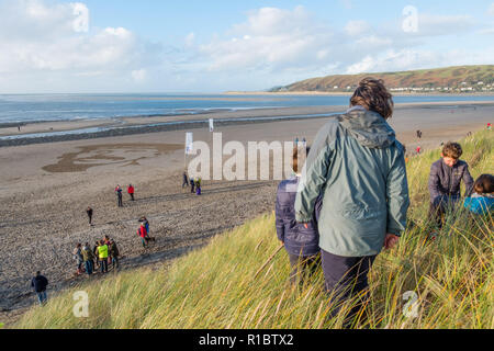 Ynyslas Wales UK, 11/11/2018. People watch as a giant 30mx30m sand portrait of RICHARD DAVIES, deck hand,  from nearby Borth village, who served in the Royal Navy in the first world war, is carved into the sand on Ynyslas Beach , just north of Aberystwyth on the west wales coast.  Devised by director DANNY BOYLE, this ephemeral pieced of memorial art  - Pages of the Sea - is one of 28 created on beaches all around the UK on this day,  Remembrance Sunday, the 100th anniversary of the armistice that brought to an end World War One  photo credit Keith Morris / Alamy Live News Stock Photo