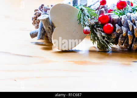 Scandinavian Christmas wreath with red berries and pine cones on a light wooden table Stock Photo