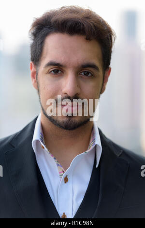 Face of young handsome Indian businessman outdoors Stock Photo