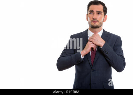 Studio shot of young handsome businessman thinking while fixing  Stock Photo