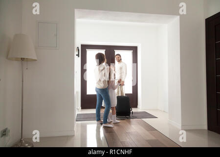 Family in hallway, father leaving home with suitcase luggage Stock Photo