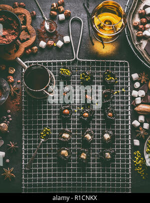 Homemade chocolate pralines preparation on dark rustic table background with vintage kitchen utensils and ingredients. Prunes filled with nuts Stock Photo