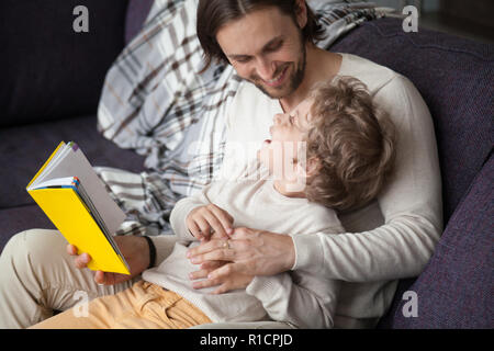 Father and son with fairytale book on couch Stock Photo