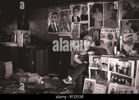 Beijing, Asia – June 6 2018: Adult man sitting on his market store and selling posters with portraits of famous Chinese leaders Stock Photo