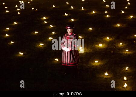 London, UK. 11th November 2018. Beefeater standing in the Tower of London moat. Beyond the Deepening Shadow is an installation where 10000 flames are lit for Rememberance Sunday. Credit: Dimple Patel/Alamy Live News Stock Photo