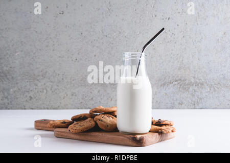 cookies and a bottle of milk with metal staws against a grey concreate background Stock Photo