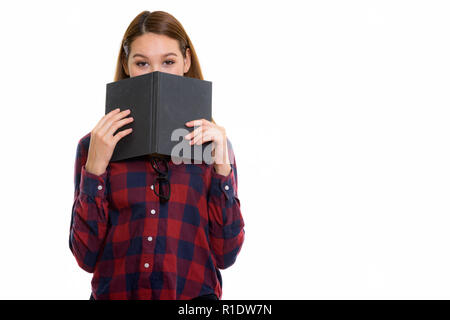 Studio shot of young beautiful Asian woman hiding behind book Stock Photo