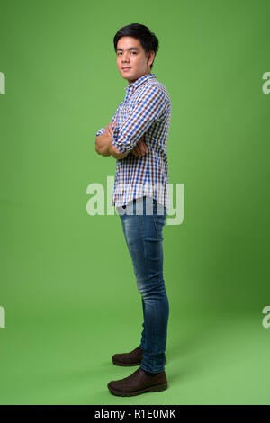 Young handsome Filipino man against green background Stock Photo