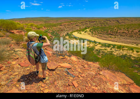 Travel photographer backpacker with stabilizer takes shot at Murchison River Gorge in Kalbarri National Park, Western Australia. Videomaker with professional camera takes photo in Australian outback. Stock Photo