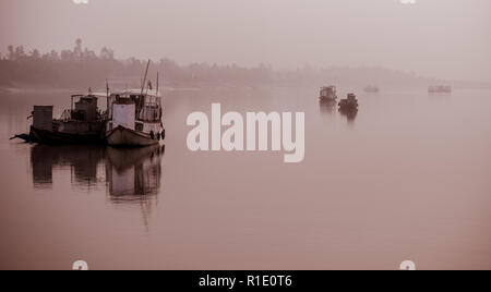 Anchored fishing boats on a foggy morning in the Subarbans, West Bengal, India Stock Photo