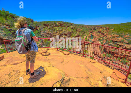 Travel photographer backpacker with stabilizer takes shot at Z-Bend lookout in Kalbarri National Park, Western Australia. Videomaker with professional camera takes photo in Australian outback. Stock Photo