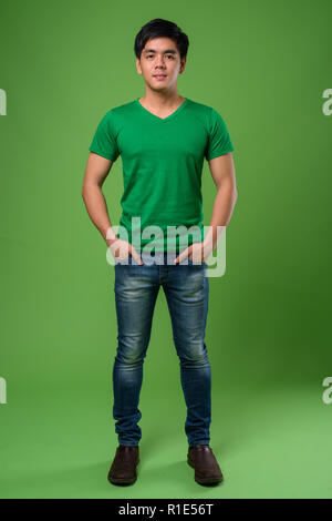 Young handsome Filipino man against green background Stock Photo