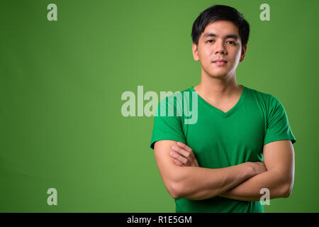 Young handsome Filipino man against green background Stock Photo